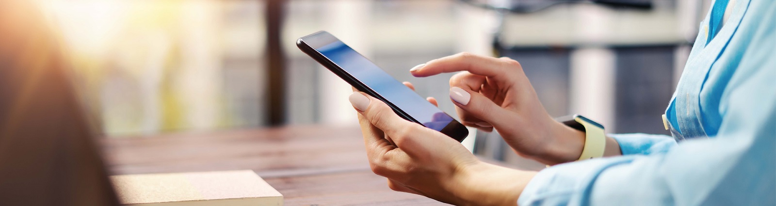 Hands of a person using a cell phone and pointing to the screen.