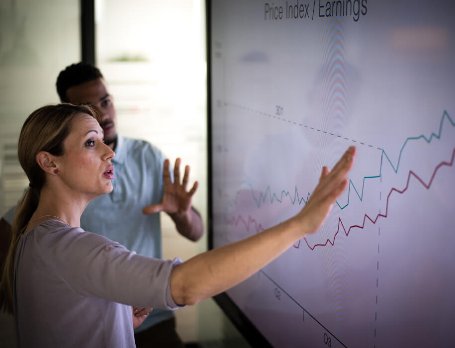 Two business people looking at an "Earnings" graph on a large screen