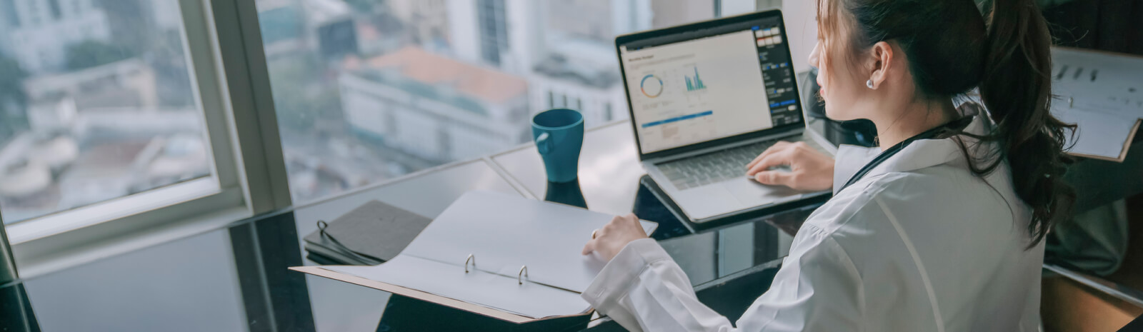 Woman in lap coat looking at charts on a laptop