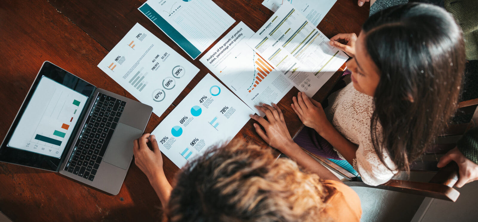 A group of business people looking over various graphs and data on paper and a laptop