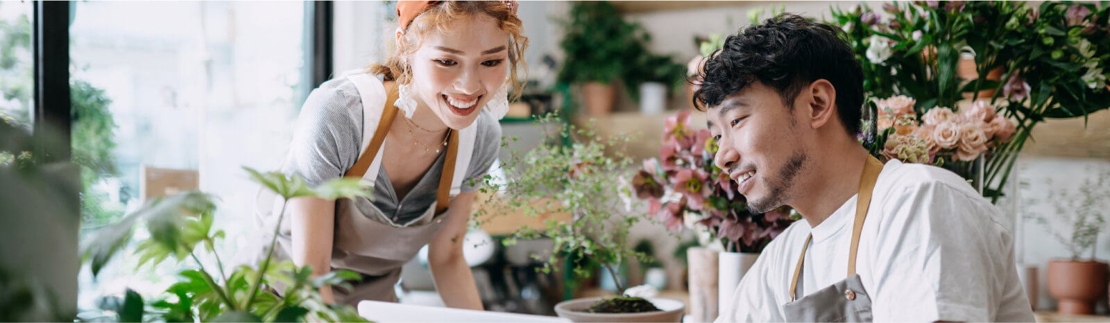 Two florists looking at a laptop surrounded by flowers