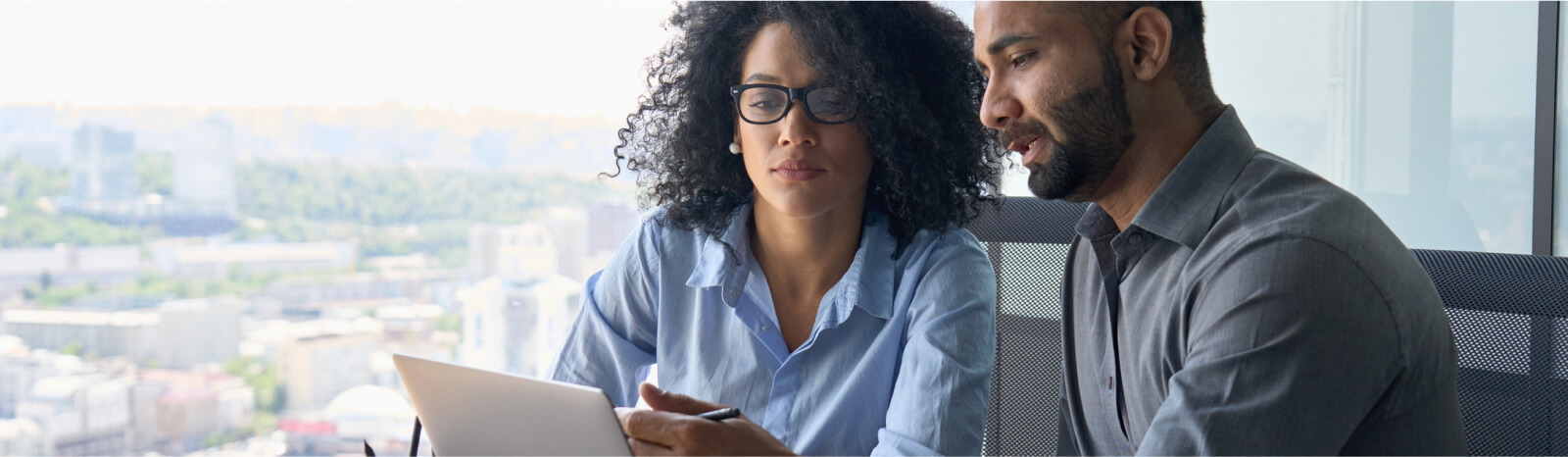 A man and woman in business attire looking at a laptop